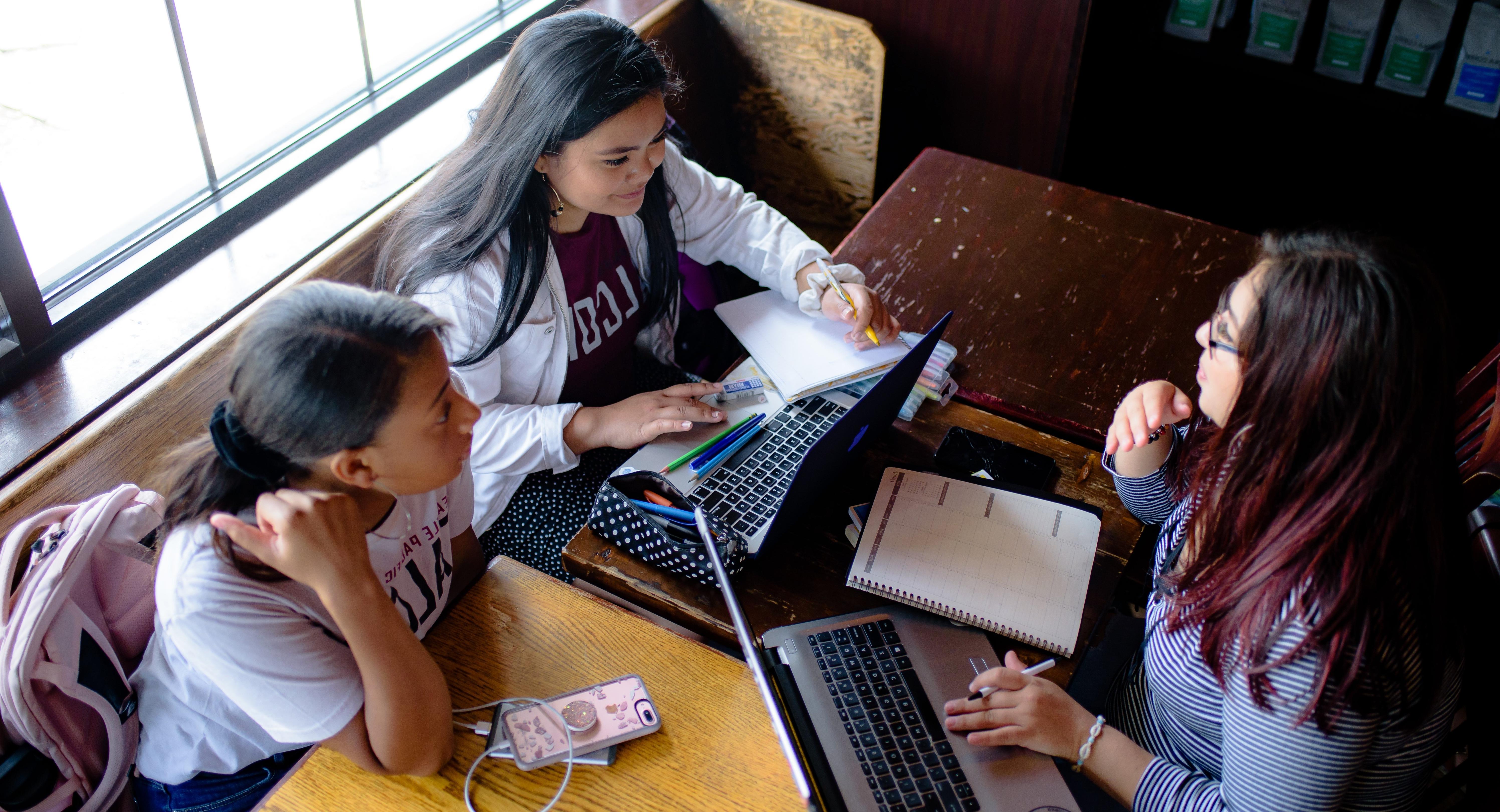 三个学生在一张咖啡桌旁一起学习
